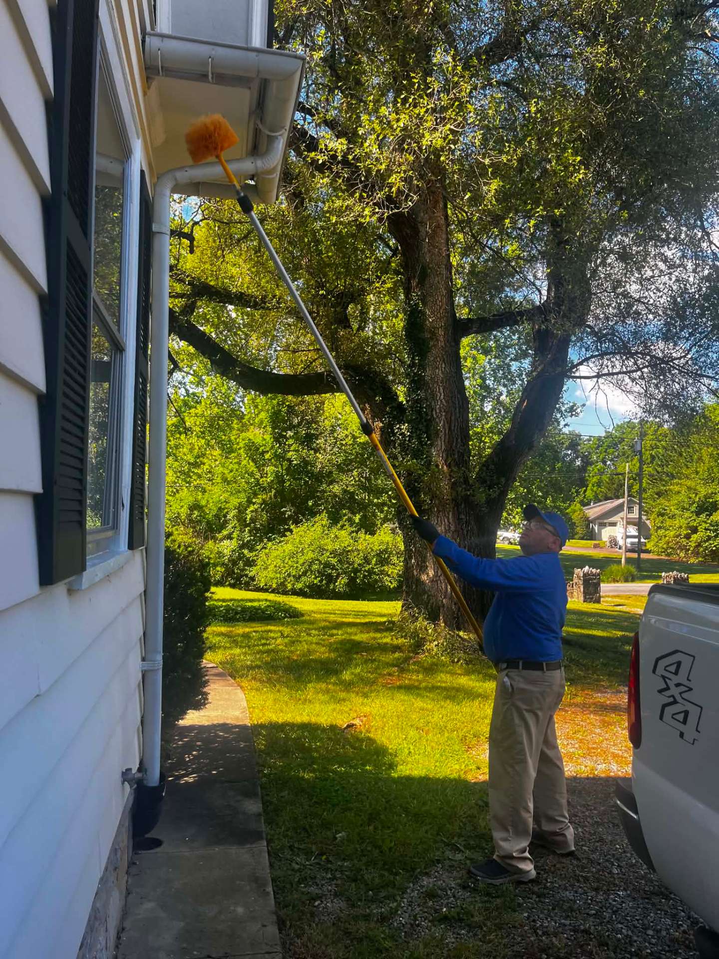 Preferred Pest Pros technician performing eave and spider web removal on a Northern Virginia home